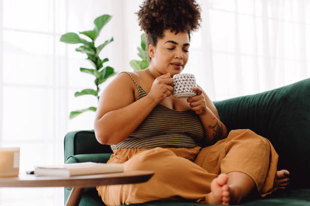 istock Pretty woman sitting on couch with coffee mug 1324533090