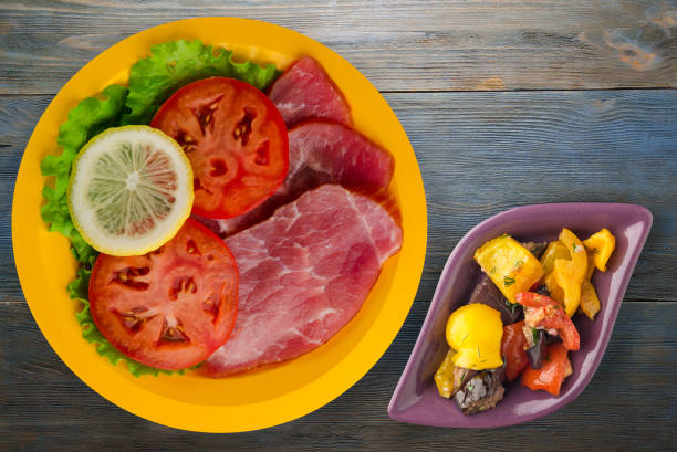 istock ham with salad, tomato and lemon on a plate. 1324535815