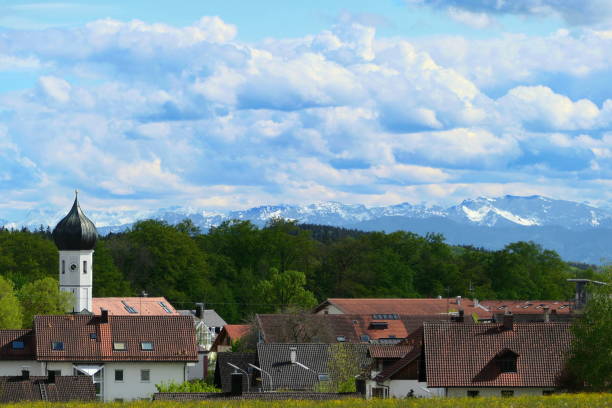Bavaria, Germany. Panoramic view of our village with characteristic Bavarian white and blue cloudy sky and the alps at the background.