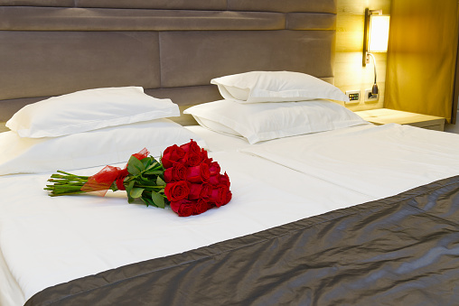 Bouquet of red roses on the bed in a hotel room. Romantic meeting of guests at the hotel honeymoon. romantic getaway for your beloved.