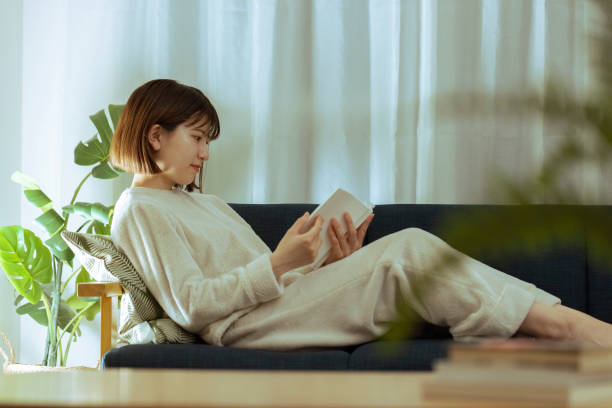 mujer joven relajándose en la sala de estar - ropa de dormir fotografías e imágenes de stock