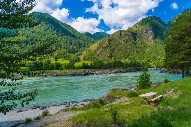 turquoise mountain river among mountains, bright cloudy sky, summer ecological camping place