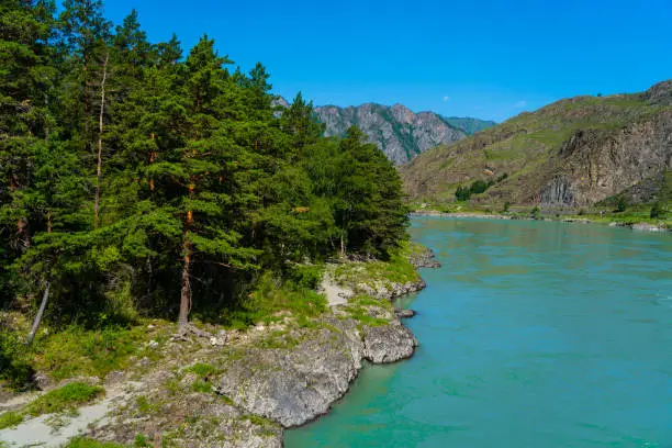 turquoise mountain river among mountains, bright cloudy sky, summer ecological rest place