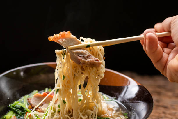 istock chopsticks picking delicious Chinese noodle and crispy pork 1324541435