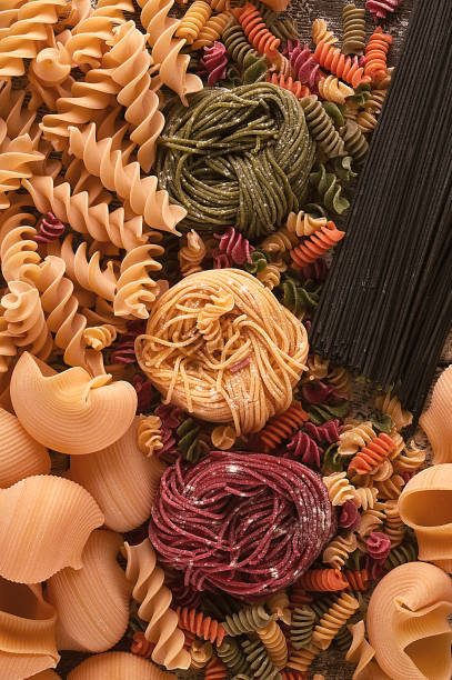 istock Pasta raw, multicolored, Italian dish, on a wooden table top view, rustic style, vertical, background, no people, 1324542816