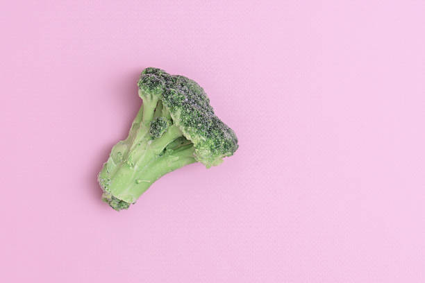 istock Single frozen broccoli on a pink background with copy space. 1324546646