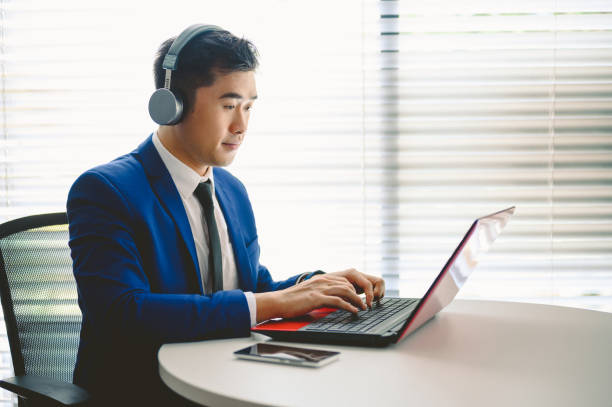 istock Young Asian businessman wearing headset while working on laptop 1324548925