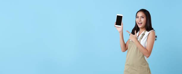 Entrepreneur asian woman showing blank screen smartphone on blue background. panoramic background.