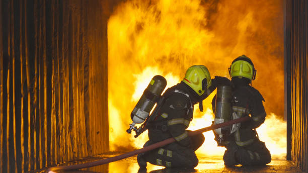 istock A group of firefighter or fireman with uniform using water fire hose against hot burning fire and dangerous smoke in the container, an emergency accident rescue. People. Hero teamwork. 1324550452