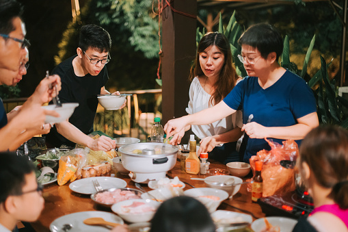 asian chinese friends and family enjoying garden party reunion dinner with hot pot traditional chinese food