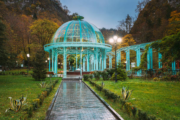 Borjomi, Samtskhe-Javakheti, Georgia. Pavilion Above Hot Spring Of Borjomi Mineral Water. Famous Local Landmark Is City Park At Autumn October Evening. Borjomi, Samtskhe-Javakheti, Georgia. Pavilion Above Hot Spring Of Borjomi Mineral Water. Famous Local Landmark Is City Park At Autumn October Evening. borjomi, samtskhe-javakheti, georgia. pabellón sobre aguas termales de agua mineral borjomi. famoso punto de referencia local es city park en otoño octubre por la noche. borjomi, samtskhe-javakheti, georgia. pabellón sobre aguas termales de agua mineral