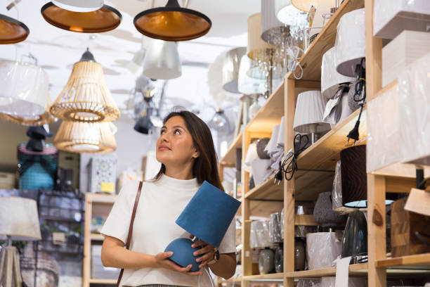 istock Smiling woman is looking on table lamps in shop 1324553530