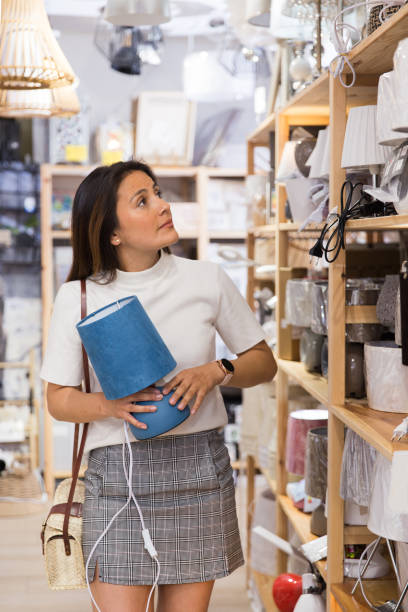 istock Young woman choosing table lamp at shop 1324553535
