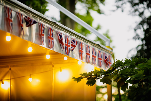 Shallow depth of field (selective focus) details with the British flag and a merchandise tent during a British themed garden party.