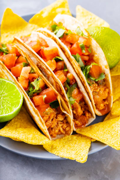 istock Mexican tacos and nacho chips on a plate. Tacos and tortilla chips on a gray background. Hispanic mexican food. Copy space. Flat lay 1324556796