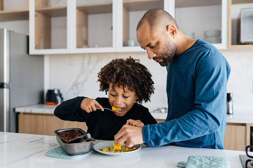 Boy having a quick snack in the kitchen with his father