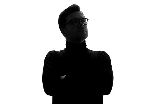 Silhouette of caucasian mature serious man in black poloneck and glasses. Studio shot