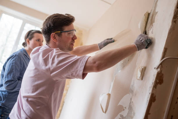 istock Young couple removing old wallpaper from walls preparing for flat renovation. 1324560224