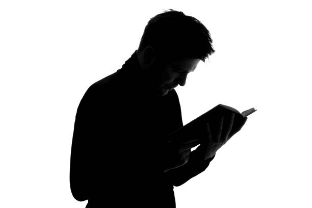 istock Silhouette of young man reading book. Student preparing for exam 1324561003