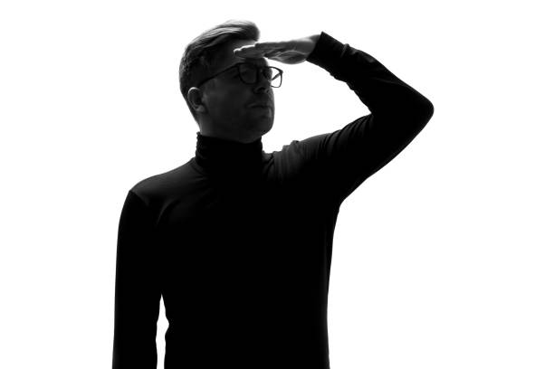 silhouette des mannes, der in die ferne blickt, mit der hand auf der stirn - staring black and white glasses human face stock-fotos und bilder