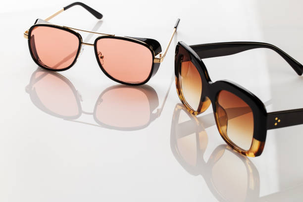 istock Sunglasses on a white reflective surface. Fashionable, stylish accessories.  Use it for a vacation or summer concept. 1324562654