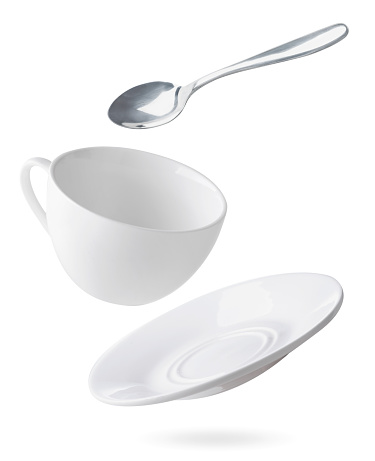 Platos vacíos taza, plato y cuchara están volando sobre un blanco. aislado photo