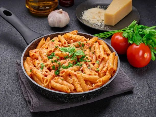 Close-up of a frying pan with Penne All'arrabbiata pasta cooked according to a traditional Italian recipe