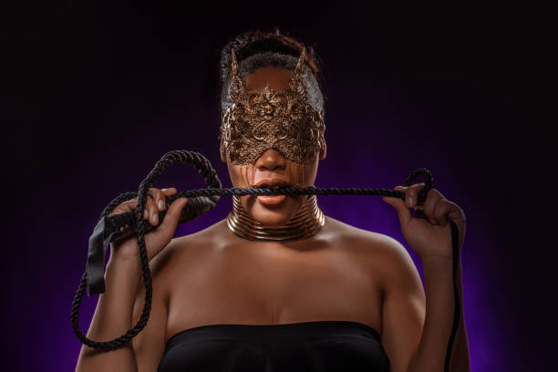 Portrait of a beautiful mixed race dominatrix woman Portrait of a beautiful mixed race dominatrix woman wearing a jewelled mask holding a whip dominatrix stock pictures, royalty-free photos & images
