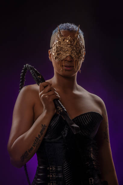 Portrait of a beautiful mixed race dominatrix woman Portrait of a beautiful mixed race dominatrix woman wearing a jewelled mask holding a whip dominatrix stock pictures, royalty-free photos & images