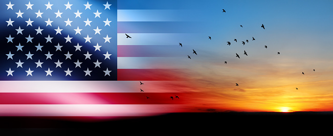 United States of America flag on bright sky at sunset or sunrise with flying birds background. USA Independence day, 4 July. Memorial day. Veterans day.