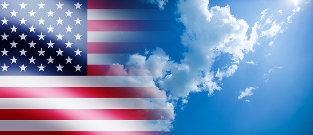 United States of America flag on the blue cloudy sky background. USA Independence day, 4 July. Memorial day. Veterans day.