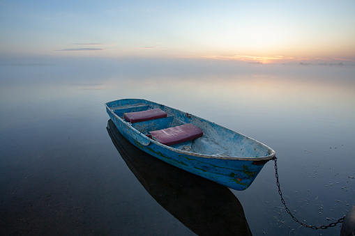 Sunrise on the lake. Lone boat on calm water.