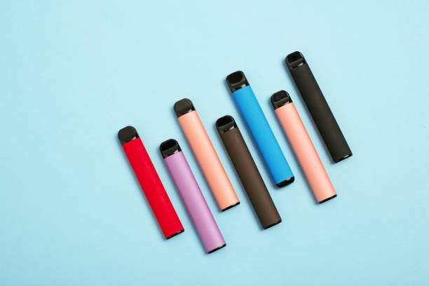 diseño de coloridos cigarrillos electrónicos desechables sobre un fondo azul. el concepto de fumar moderno. vista superior - cigarrillo electrónico fotografías e imágenes de stock