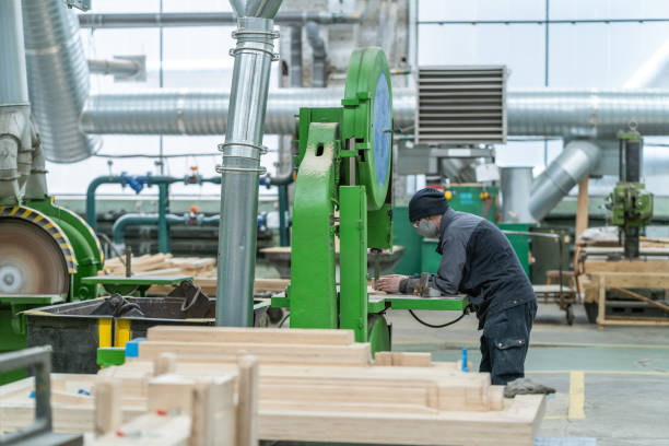 istock Unrecognizable worker mask in timber workshop works with big grinder machine tool at woodworking plant interior 1324572412