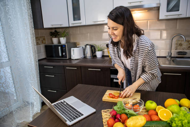 istock woman cooking checking recipe at laptop 1324572570