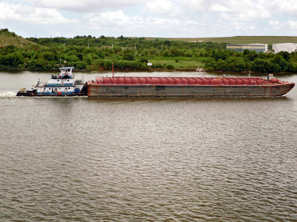 istock tug pulls barge ship into port on the water 1324574625