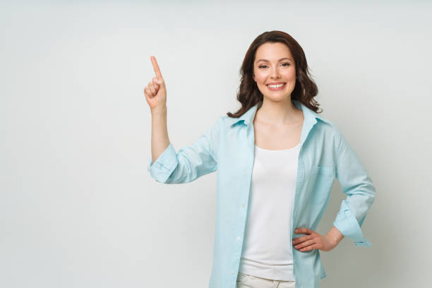 istock Young woman smiling and gesturing to copy space 1324577084