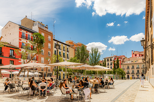 June, 2021. Madrid, Spain. A sunny day in the old town of Madrid with several young people, colorful buildings and deep blue sky with few clouds.
