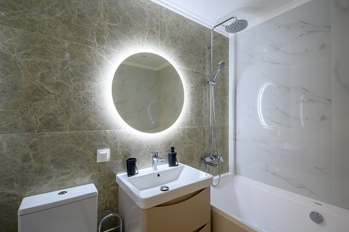 hotel bathroom toilet with dark gray stone tile walls, wood floor, Shower near the window and sink on wooden countertop with round mirror. with wooden decoration 3d rendering