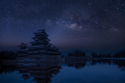 Old castle in japan. Matsumoto castle against night sky. Castle in Winter with milky way on sky .Travel Matsumoto Castle with frozen pond in Winter. A  Japanese premier historic castles