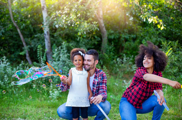 istock Happy family playing soap bubbles in park. 1324581054