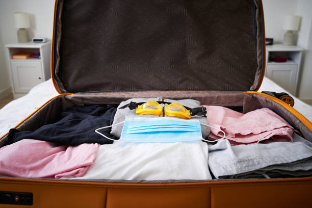 istock Open suitcase with a medical mask and a swimming goggle. 1324581636