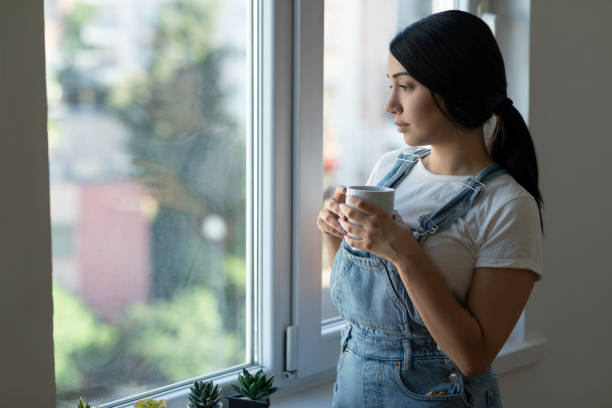 istock Woman drinking coffee near window 1324583406