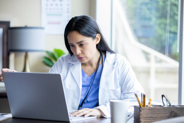 operatore sanitario che lavora su laptop in ufficio - laptop doctor using computer nurse foto e immagini stock