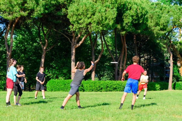 캐주얼 한 젊은 청소년의 그룹은 공원 oudoors에서 비행 플라스틱 디스크 게임 재생. 남자와 여자는 경기에서 팀원에게 디스크를 던져. 재미 를 가지고 외부 마일레니얼 친구 - men summer passing tossing 뉴스 사진 이미지
