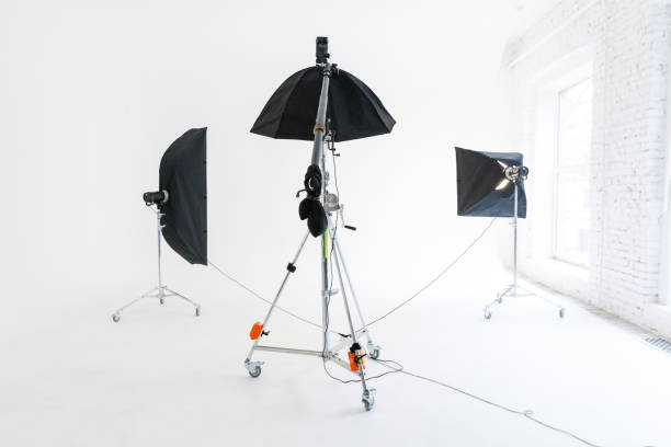 istock Empty photo studio with lighting equipment. Photographer workplace interior with professional tool set gear. Flash light white background scenes ready for studio shooting. Modern photographer studio 1324589464