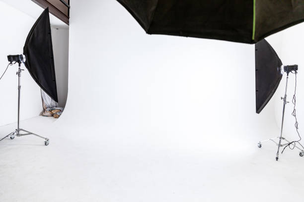 istock Empty photo studio with lighting equipment. Photographer workplace interior with professional tool set gear. Flash light white background scenes ready for studio shooting. Modern photographer studio 1324589495
