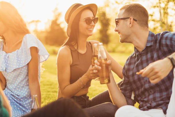 istock young woman in a summer hat and sunglasses communicates with a young man drinking drinks on a picnic in the park 1324593451