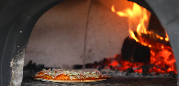 istock Authentic traditional wood fired pizza oven alight with a near cooked pizza ready at the front. 1324599550