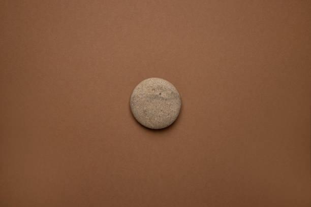 istock Rounded gray striped stone on brown background , trend minimal style 1324603444